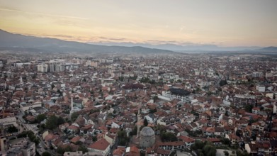 Extensive view of the city in evening light with mosque and mountains on the horizon, Prizren,