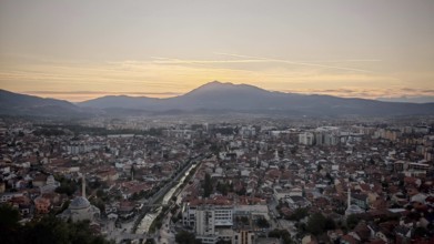 View of a city at sunset with river surrounded by mountains in the distance, Prizren, Kosovo
