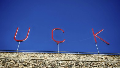 Large KLA lettering on a stone wall under a blue sky, Prizren, Kosovo