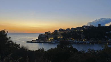 Coastal town at sunset, illuminated silhouette and calm sea, Ulcinj, Montenegro