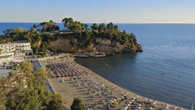 Sunny beach area with umbrellas and clear, blue sea on the coast, Montenegro