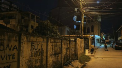 Dark street scene with graffiti and illuminated street lamps creates a tense atmosphere, Tirana,