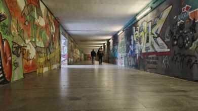 Long tunnel with colorful graffiti on the walls, some people can be seen in the background, Prague,