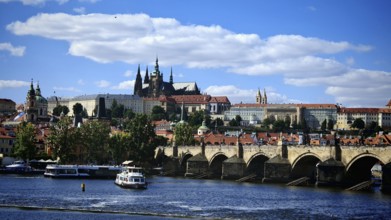 Historic bridge over a river with impressive architecture in the background under blue sky, view of