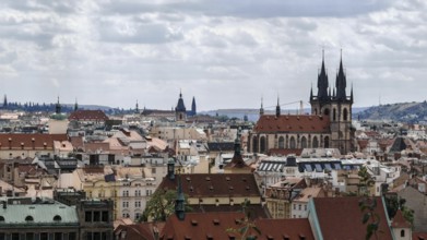 Historic city landscape with distinctive towers and roofs under a cloudy sky, Prague, Czech
