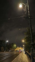 An illuminated street with street lamps and historic buildings at night, Prague, Czech Republic