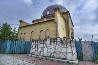 Destroyed synagogue under reconstruction, in front a wall of remembrance, constructed fragments of