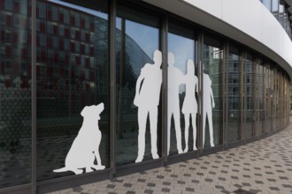 Paper cut family with dog, sticker on window front of an office building, Medienhafen Düsseldorf,