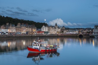 Oban, Argyll and Bute, Scotland, UK. A red traditional fishing boat in the port of Oban and old