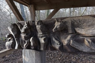 Tree trunk with carved animal figures, fox owl, squirrel, covered rest area in the forest, Kalkumer