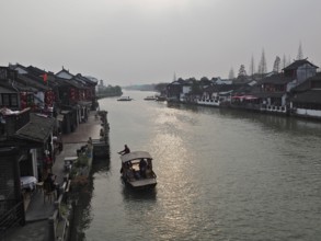 A leisurely evening view across the canal with traditional buildings and boat traffic, Zhujiajiao