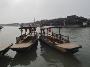 Two traditional boats with lanterns anchor on a quiet river in a Chinese city, Zhujiajiao Ancient