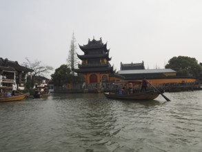 A riverbank pagoda with boats on water in a traditional Chinese landscape, Zhujiajiao Ancient Town,