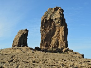 Two huge rock formations under a blue sky with people in the distance, Roque Nublo, Gran Canaria,
