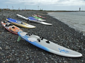 Pebble beach with colorful surfboards at sea under cloudy sky, Pozo Izquierdo, Gran Canaria, Canary