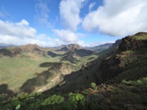 Wide mountain landscape with green valleys and dramatic cloudy sky, Barranco de Fataga, Gran