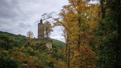 Old castle on hill in autumn landscape with cloudy sky and colorful trees, Upper Franconia
