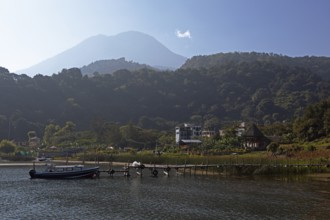 Colourful boats in the port of San Juan la Laguna, behind the Dan Pedro volcano in the haze,