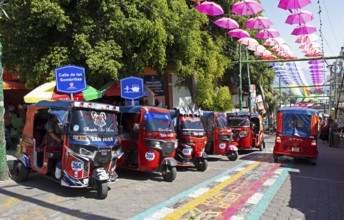 Red tuk tuks or tricycle taxis in an alley in San Juan la Laguna, Atitlán, Sololá Department,