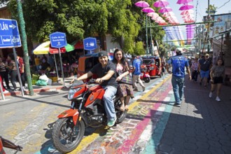 Mayans wearing traditional and modern clothes on a motorcycle in an alley in San Juan la Laguna,