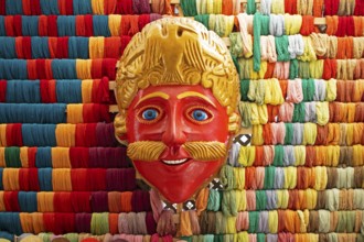 Mask of a Moro or Moor for traditional mask dance, behind a wall full of colorful cotton,