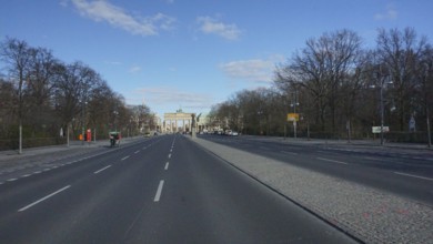 Empty street leads to the Brandenburg Gate under a blue sky, deserted during corona, Berlin