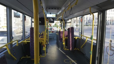 Interior of a public bus with empty seats, partly cordoned off with safety tapes and railings