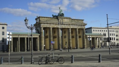Famous gate in Berlin, Brandenburg Gate with a few bicycles in the foreground and blue sky,