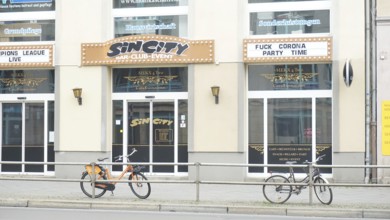 Club façade with posters and two bicycles in the foreground and sign Fuckcorona during corona,