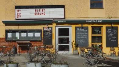 Small café with outdoor seating area and menu boards when the sun is shining with stays healthy and
