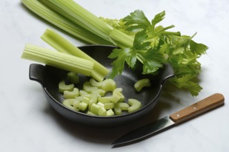 Celery stalks, pieces with knife in pot