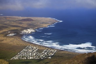 Wide coastline with bright waves and the seaside village of Caleta de Famara by the sea, Mirador de