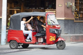 Red tuk tuk or tricycle taxi with Guatemalan passengers in Panajachel, Atitlán, Sololá Department,