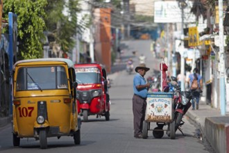 Guatemalan ice cream vendor and tuk tuks or tricycle taxis on a street in Panajachel, Atitlán,