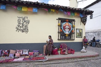 Mayan woman wearing traditional clothing on a decorated house façade, Chichicastenango market,