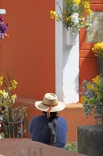 Mayan woman wearing straw hat looking at a colorful grave in the cemetery in Chichicastenango,