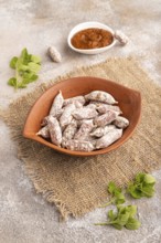 Small smoked Chicken sausages in clay bowl on brown concrete background and linen textile. side