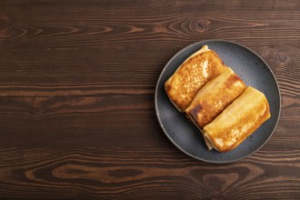 Fried crispy pancakes with meat and cheese on brown wooden background. top view, flat lay, copy