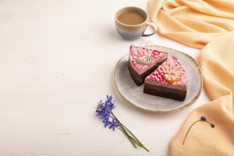 Chocolate cake on white wooden background and orange linen textile, cup of coffee, side view, copy