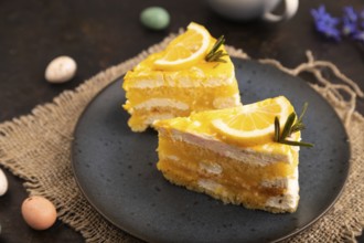 Lemon cake on black concrete background and linen textile, cup of coffee, side view, close up,