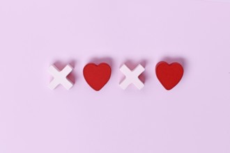 Valentine flat lay with wooden light pink and red hearts forming XOXO letters arranged on a pink