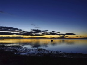 A boat on a calm lake at dusk with dramatic clouds and warm colors, Baltic Sea, Germany