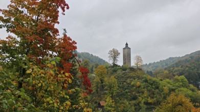 Historic tower on a wooded hill with colorful autumn leaves in a peaceful landscape
