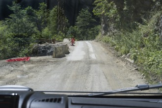 Narrow dirt road leads through wooded mountains, road 7 partly slipped down, west of Mestia,