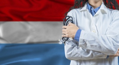 Healthcare professional with Luxembourg flag background. Professional doctor holding stethoscope on