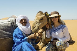 Young woman with Berber and dromedaries in the sand dunes, near Merzouga, Meknès-Tafilalet region,