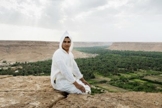 Young man and oasis in the background, near Merzouga, Meknès-Tafilalet region, Erg Chebbi, northern