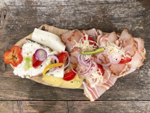Typical snack on the alpine pasture, bacon bread and cheese bread on wooden plate on wooden table,