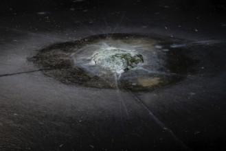 Mossy rock surrounded by cracks in a frozen lake, Finland