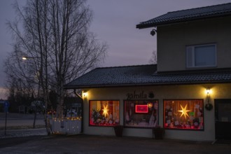 Christmas decorated and illuminated shop window with poinsettias and fairy lights, blue hour,